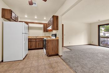 A kitchen with a white refrigerator and brown cabinets. at Windsor Crest Apartments, Iowa